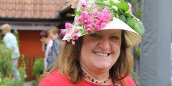 Eine Frau strahlt mit einem mit Blumen geschmückten Sonnenhut (SF)